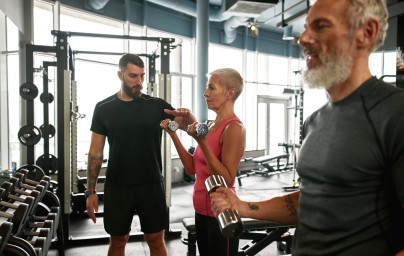 Trening siłowy na siłowni – grupa osób ćwiczących z hantlami pod okiem trenera