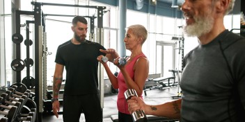 Trening siłowy na siłowni – grupa osób ćwiczących z hantlami pod okiem trenera